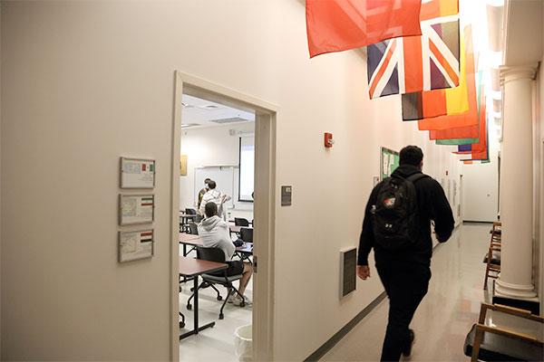 一名学生走出教室时走在一组国际旗帜下